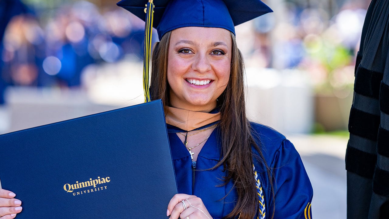 A student smiling with their diploma