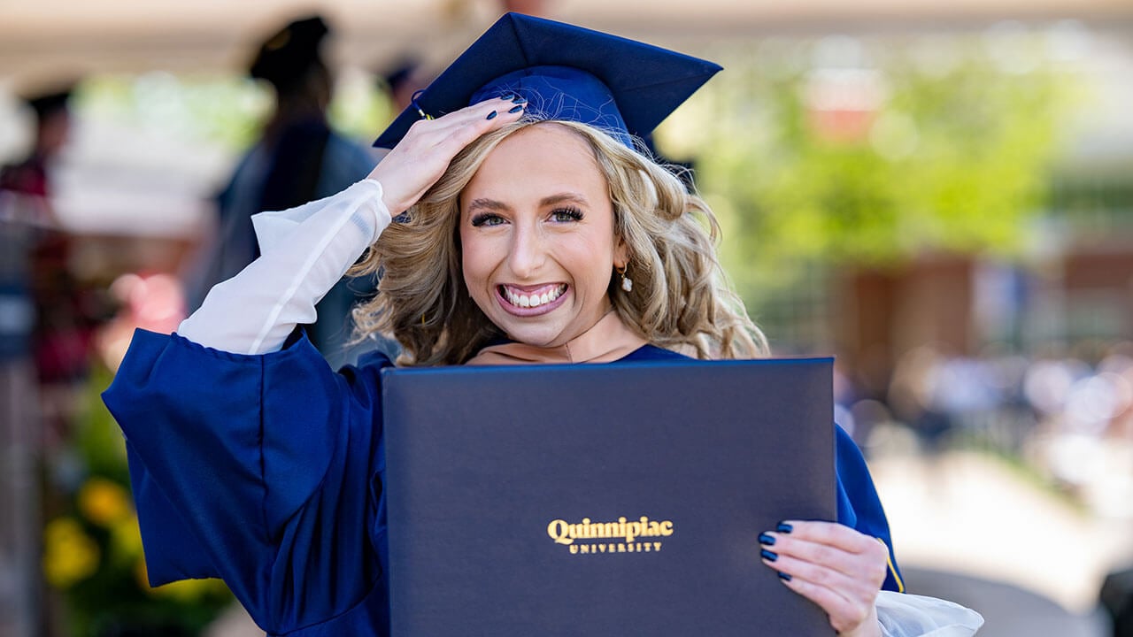 I student smiling widely as they walk off of the commencement stage