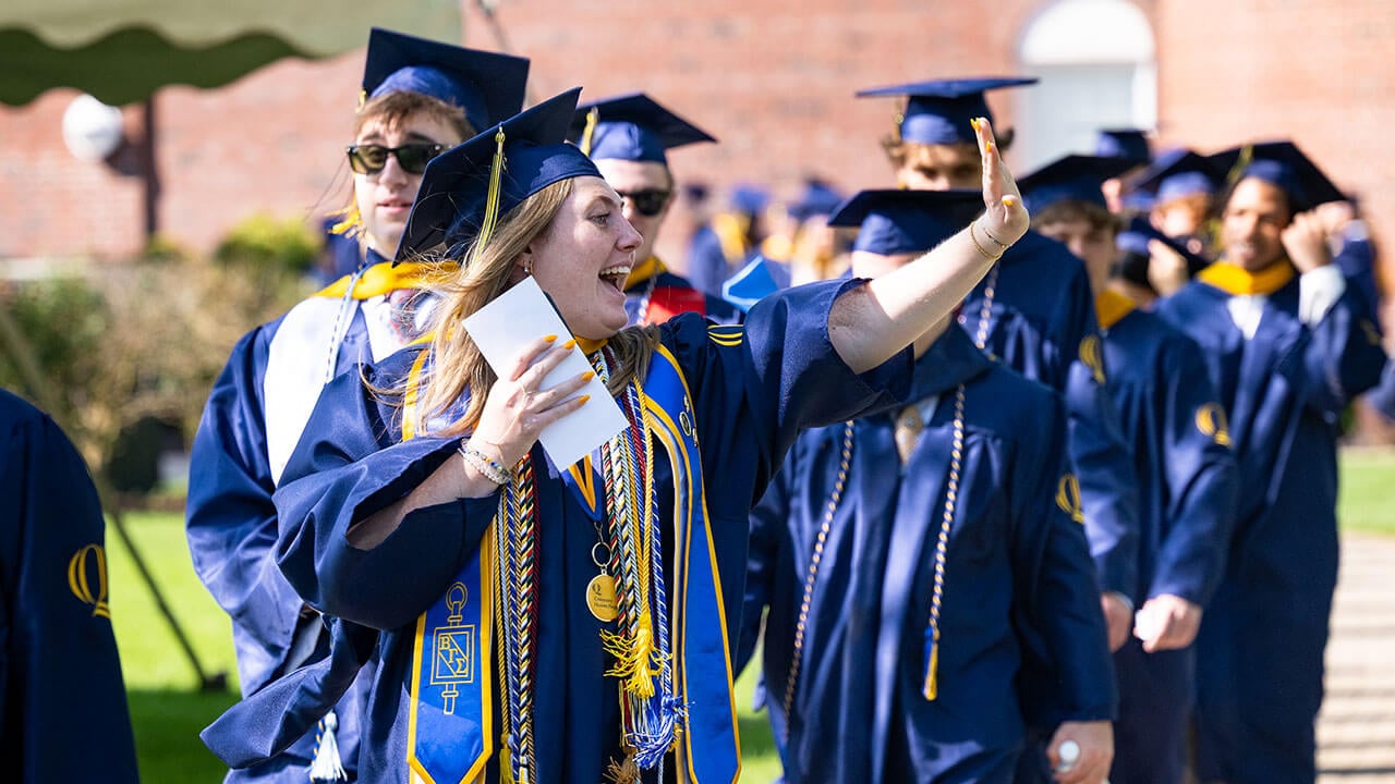 A graduate waving into the distance