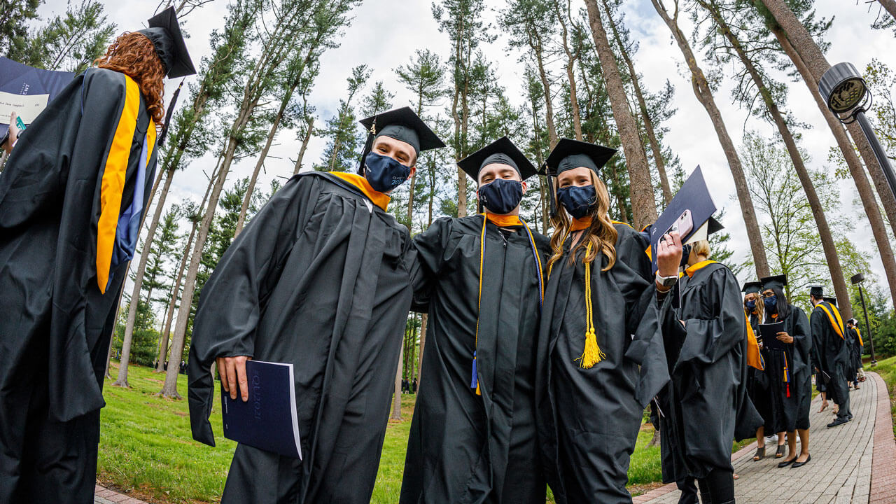 3 students standing together in pine grove