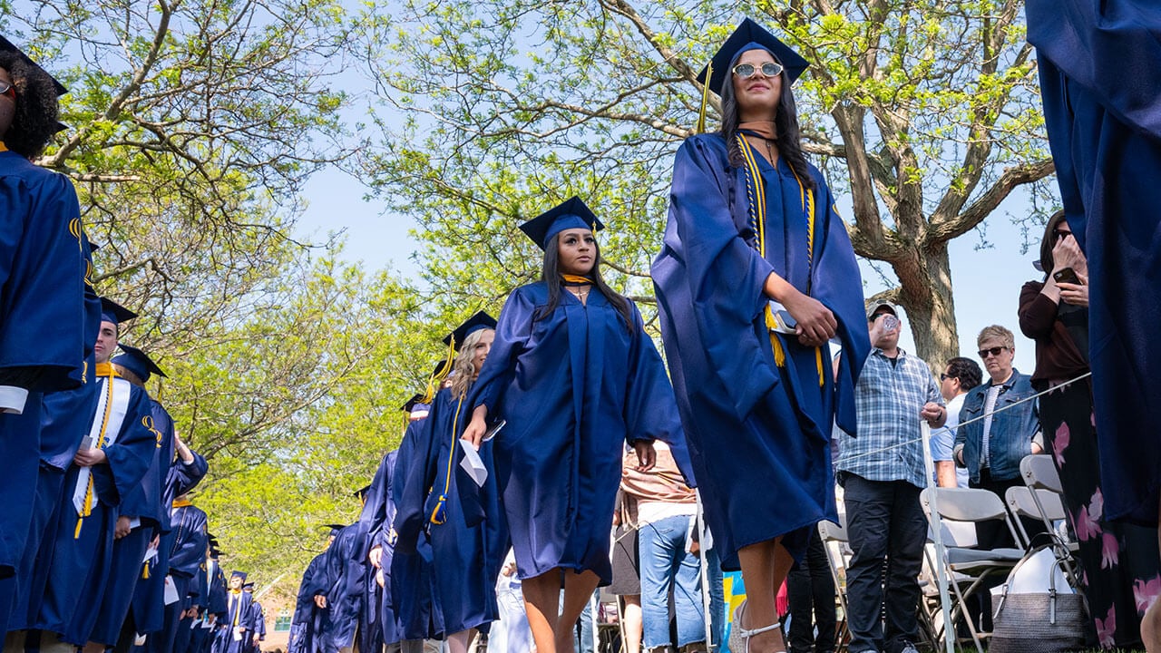 Graduates walk across campus to their seats during commencement