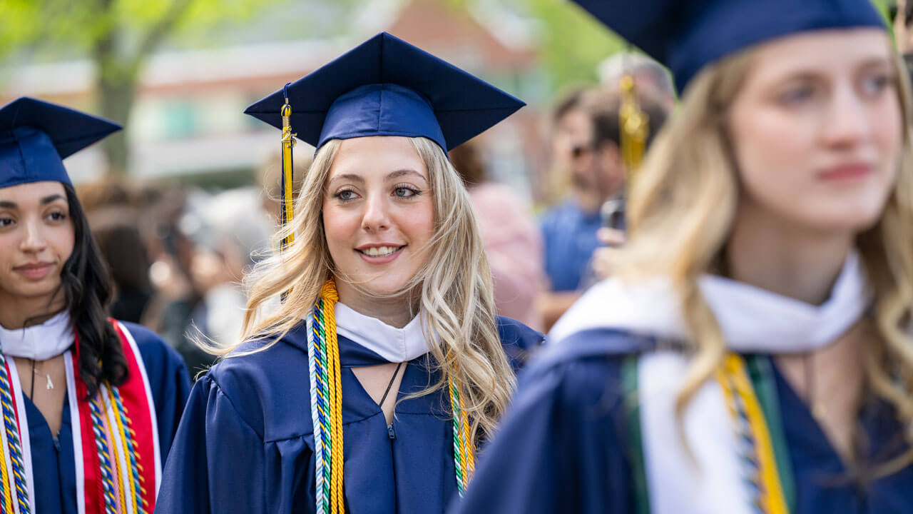 Graduate smiles while walking in procession