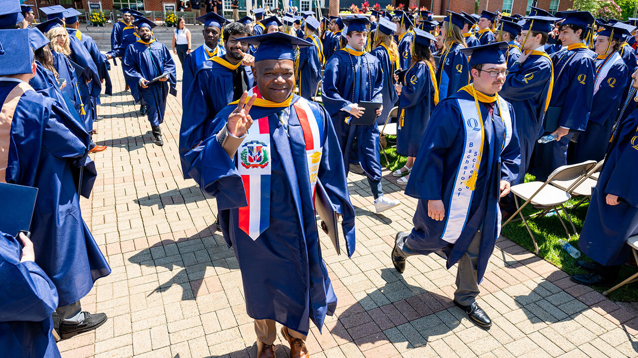 A graduate holding up a peace sign after receiving their diploma