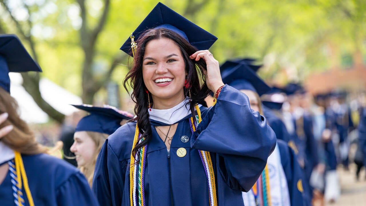 Graduate smiles while walking in procession