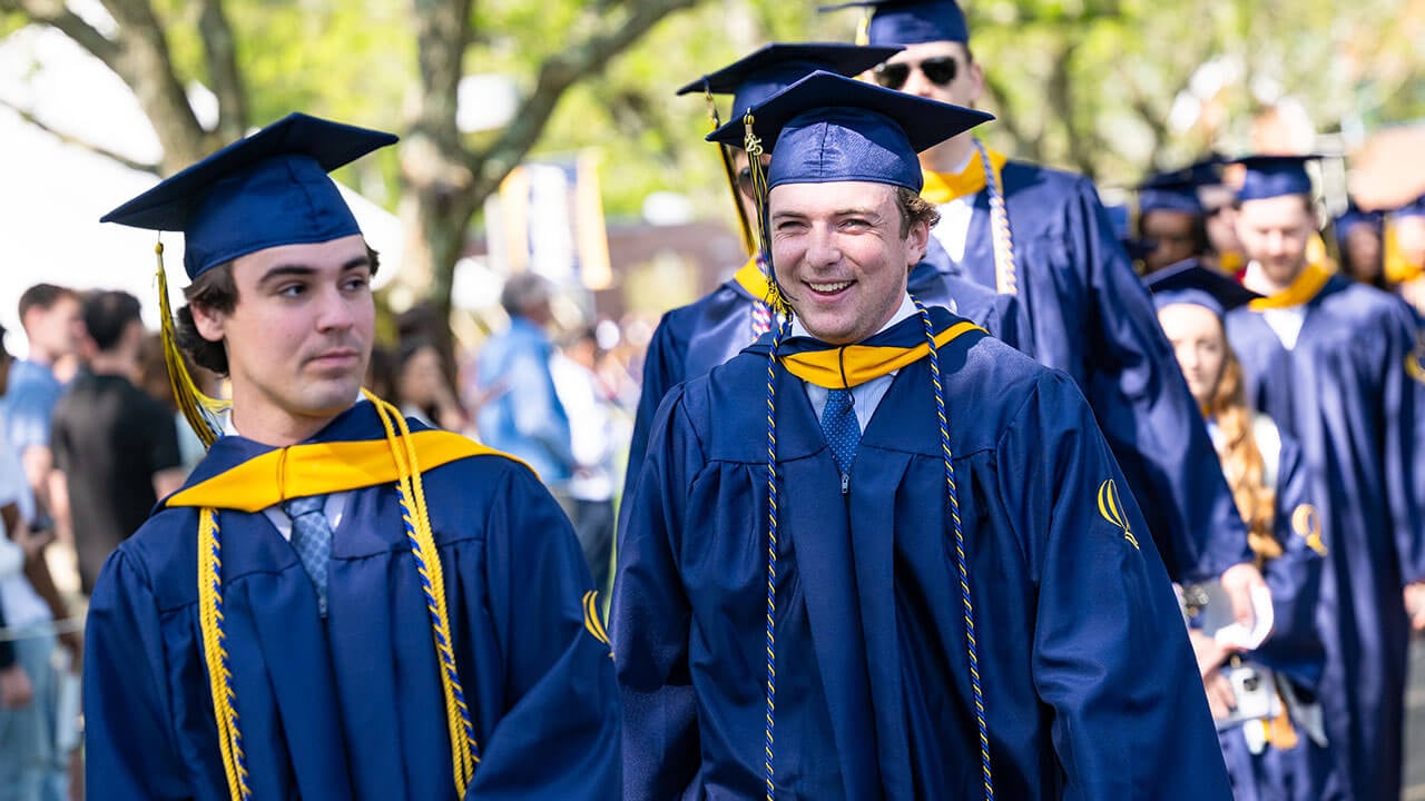 A graduate laughing as he processes in for commencement