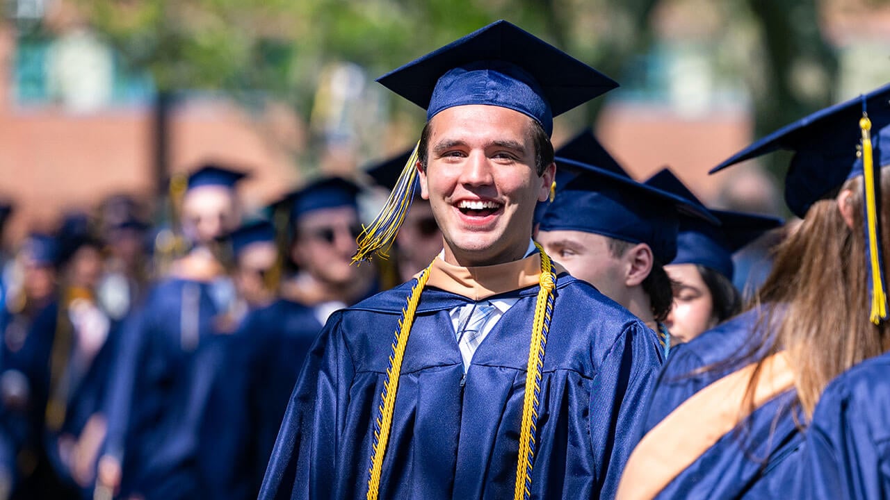 A graduate in the procession line laughs