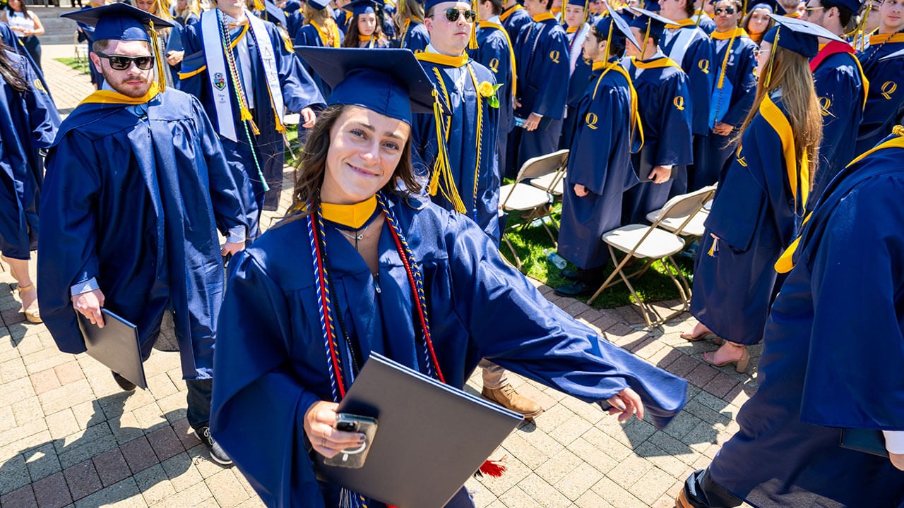 A graduate walking and smiling after receiving their diploma