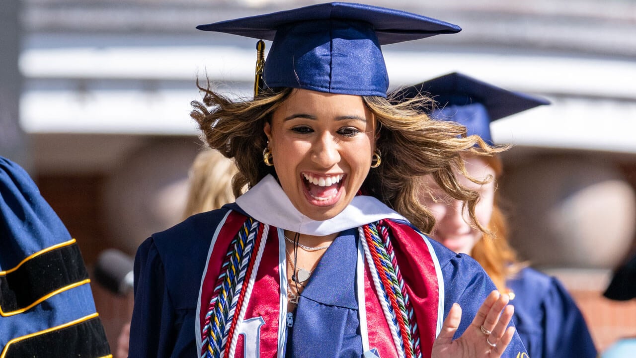 Graduate smiles as she walks off the commencement stage.