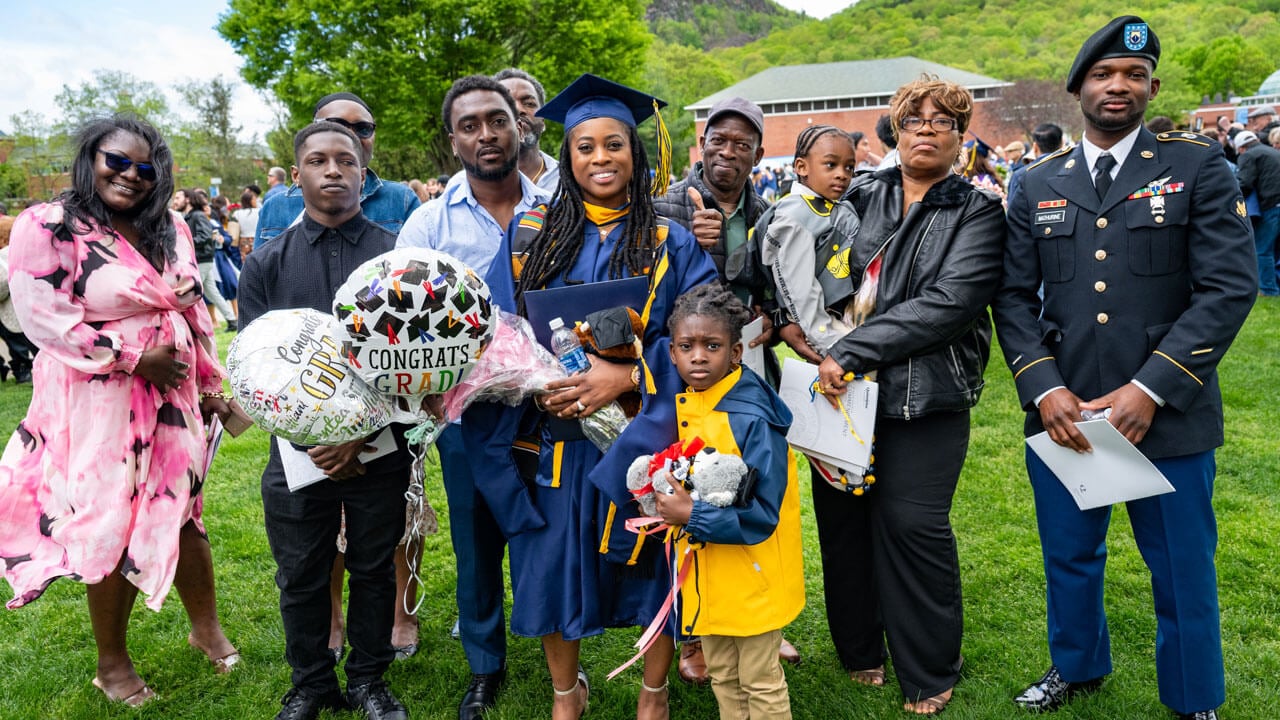 Graduates poses with their loved ones holding balloons.