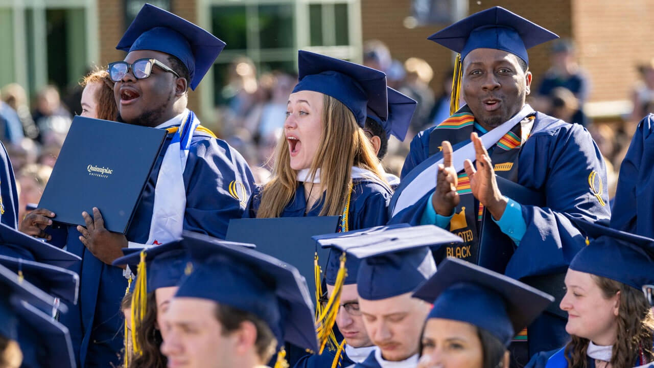 Graduates clap and cheer from the crowd.