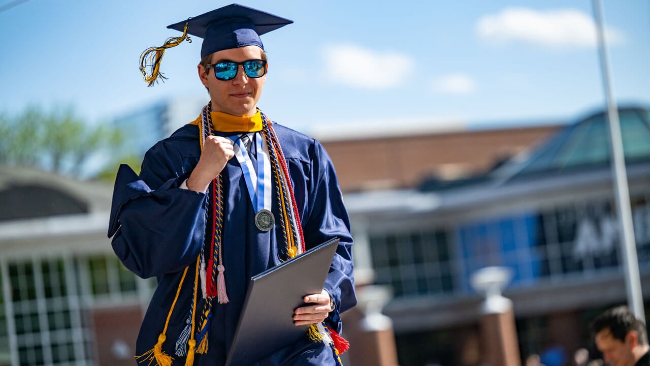 Graduate shakes his fist as he walks off the commencement stage with their diploma.