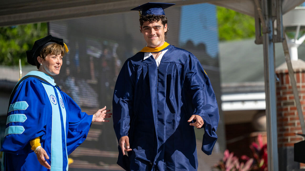 Graduate walks across the commencement stage.
