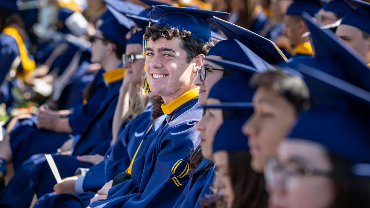 Graduate smiles from their seat.