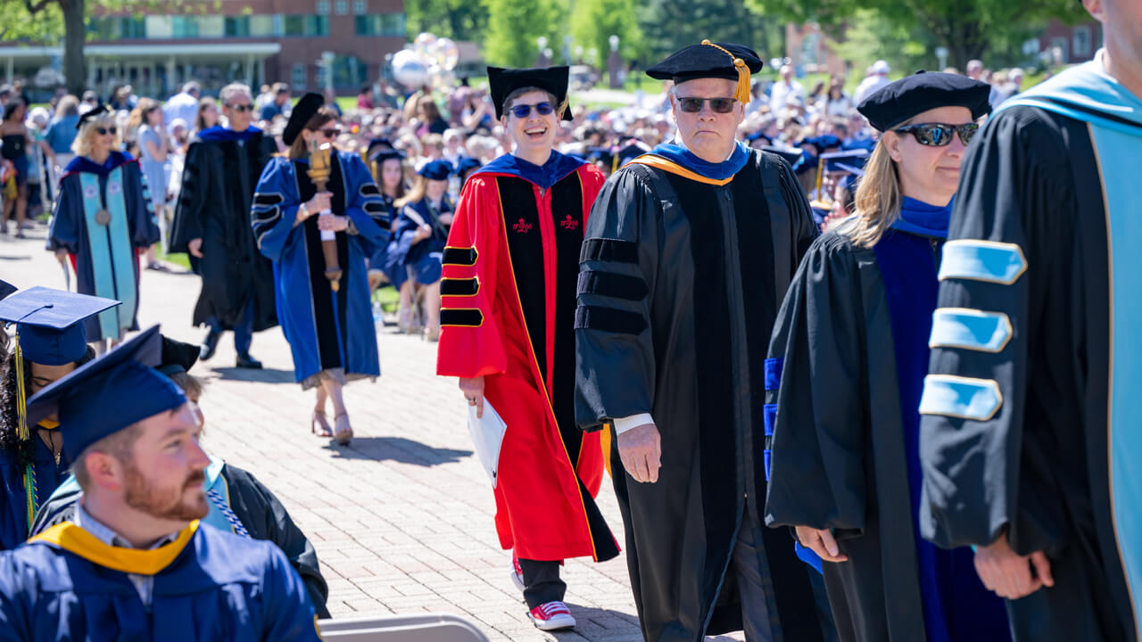 Deb Liebowitz laughs as she she walks into Commencement wearing her red commencement robes