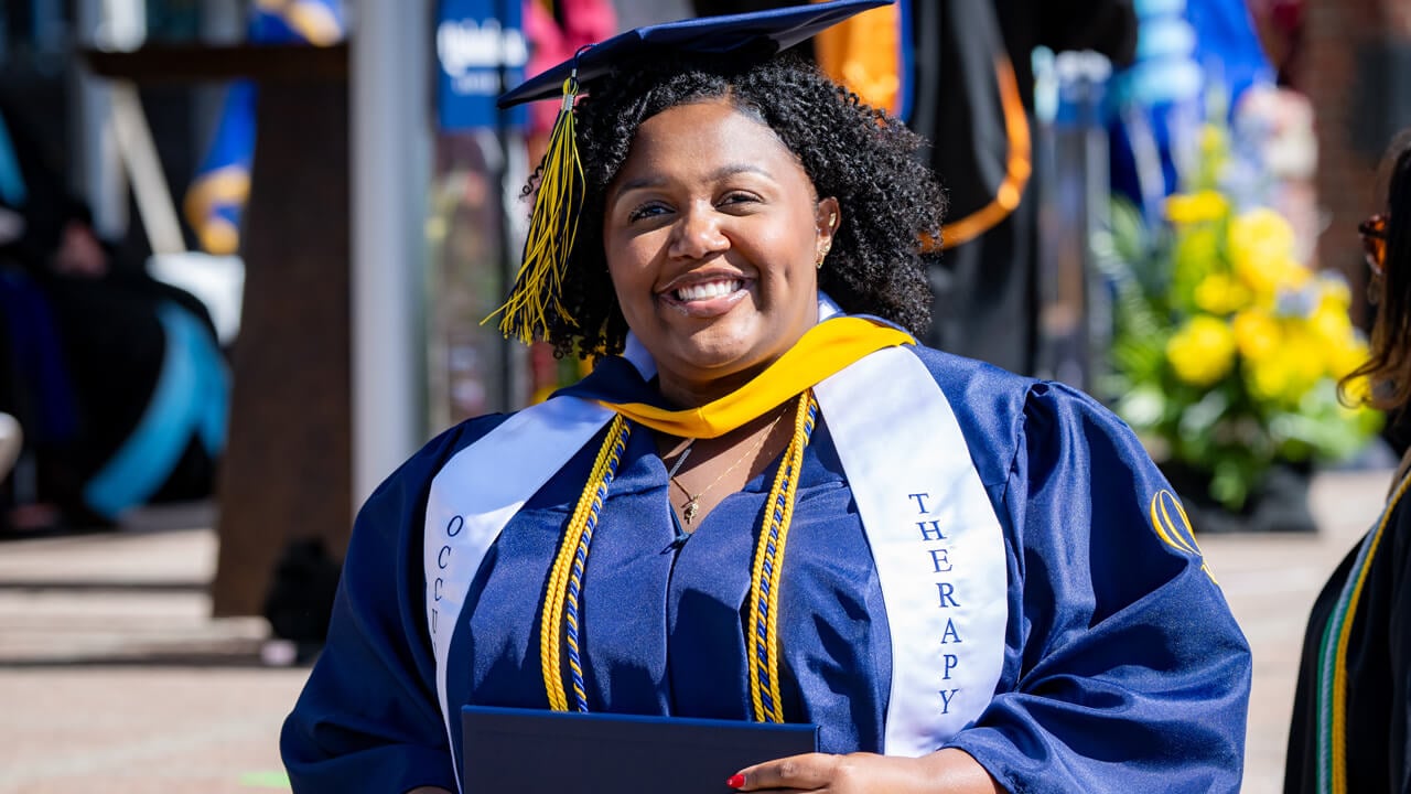 A grad smiling with their diploma
