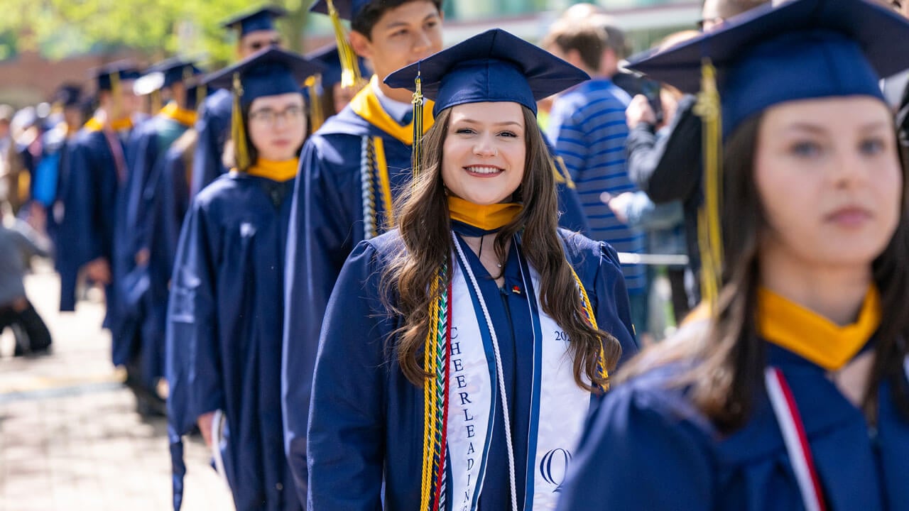 Graduate smiles while walking in procession