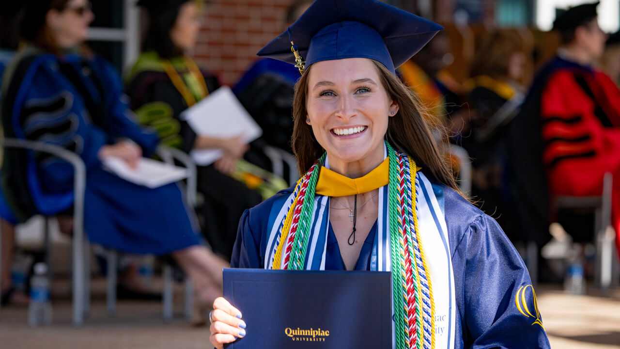 A grad smiling with their diploma