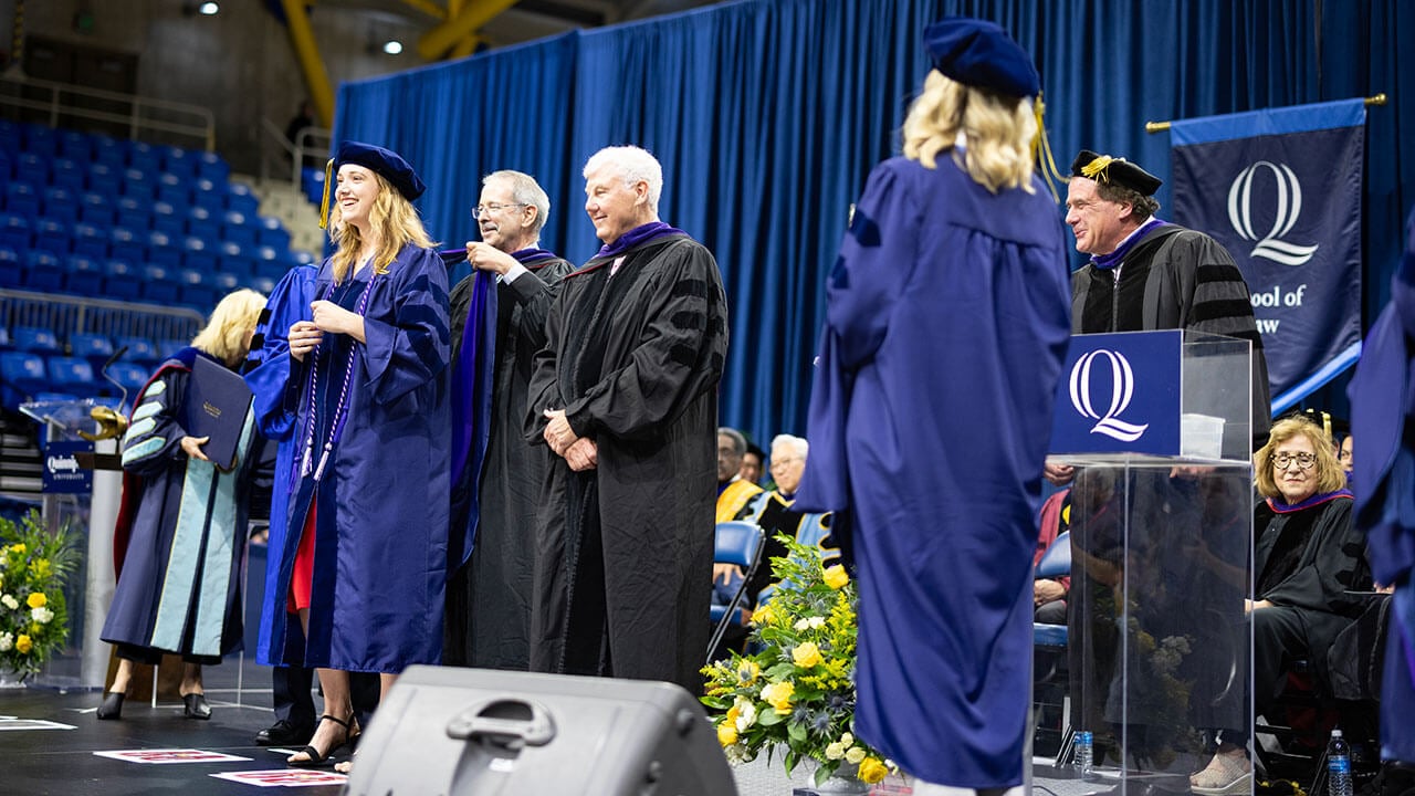 A Quinnipiac Law graduate getting hooded on the commencement stage