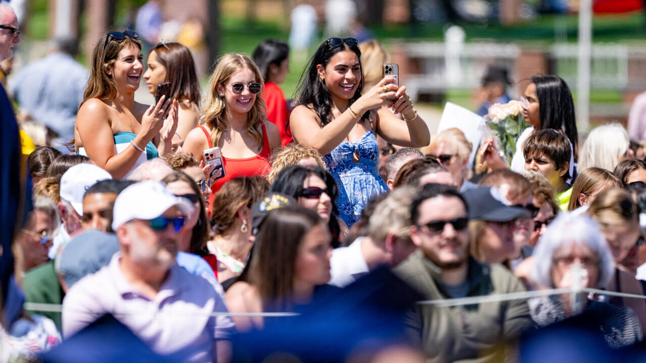The crowd cheers and takes photos of commencement.
