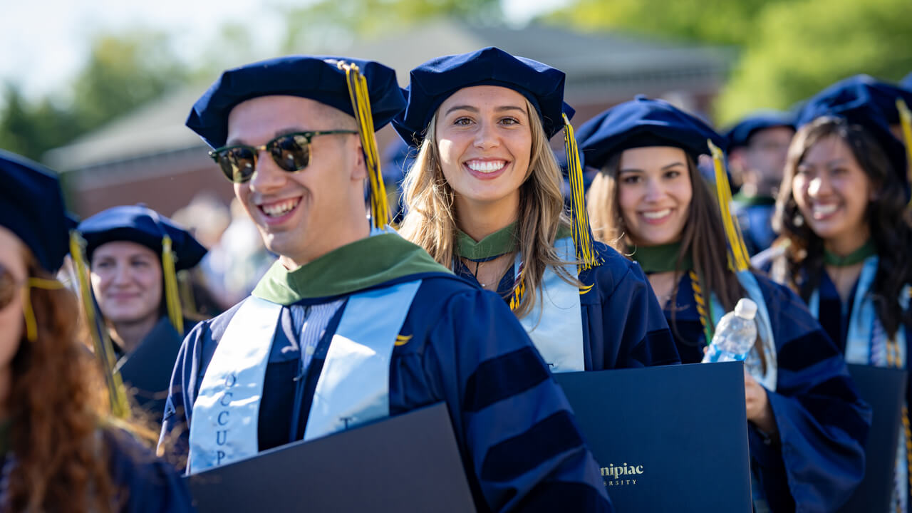 Doctor of occupational therapy graduates smile as they walk to the stage