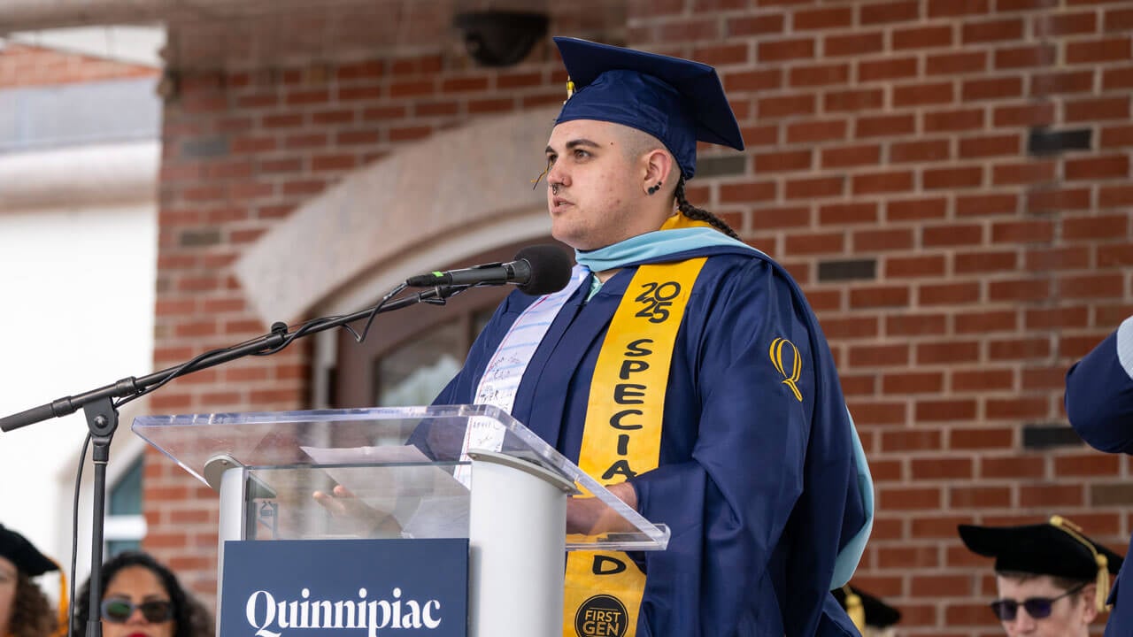 A student speaking at commencement in a cap and gown