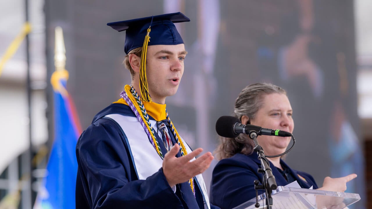 A student speaking at commencement in a cap and gown