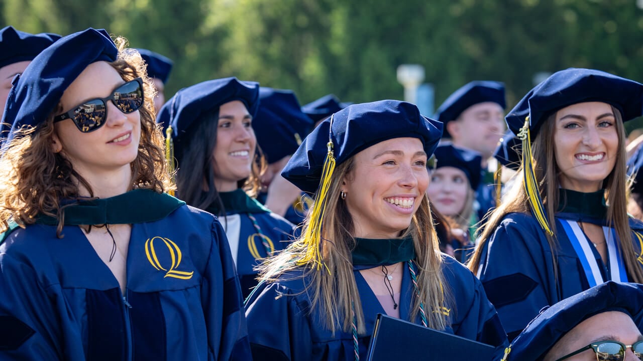 Graduates stand and smile.