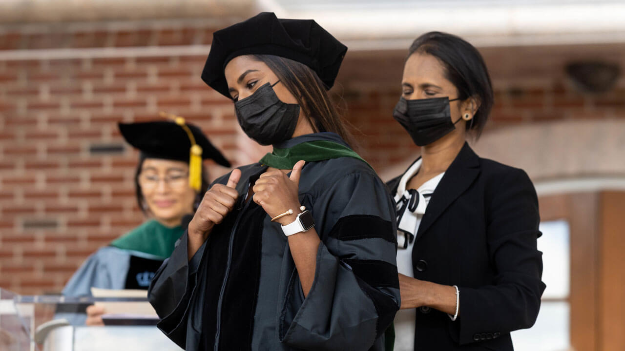 School of medicine graduate giving thumbs up after receiving her hood