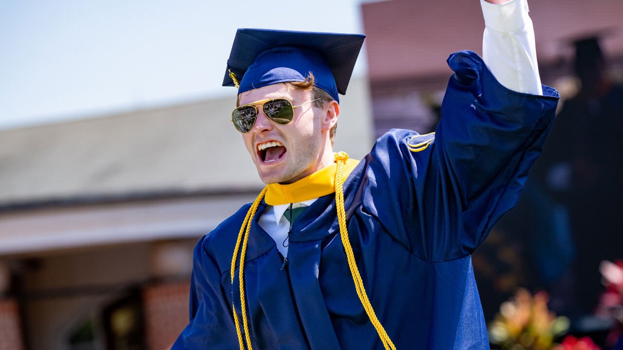 Graduate raises their hand up in excitement.