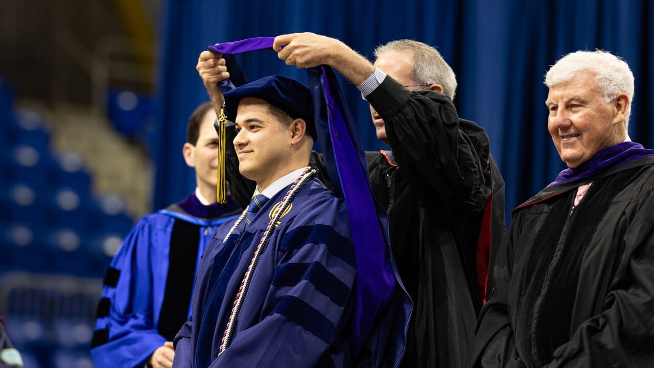 Graduate looks proud while receiving his hood