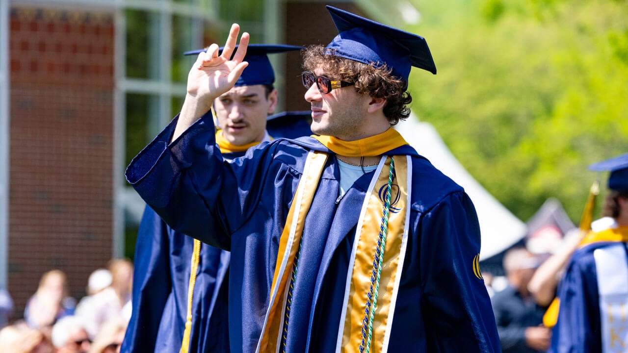 Graduate waves as they process into commencement.