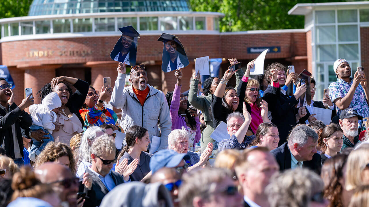 A group of family members hold up signs and cheer for their graduate