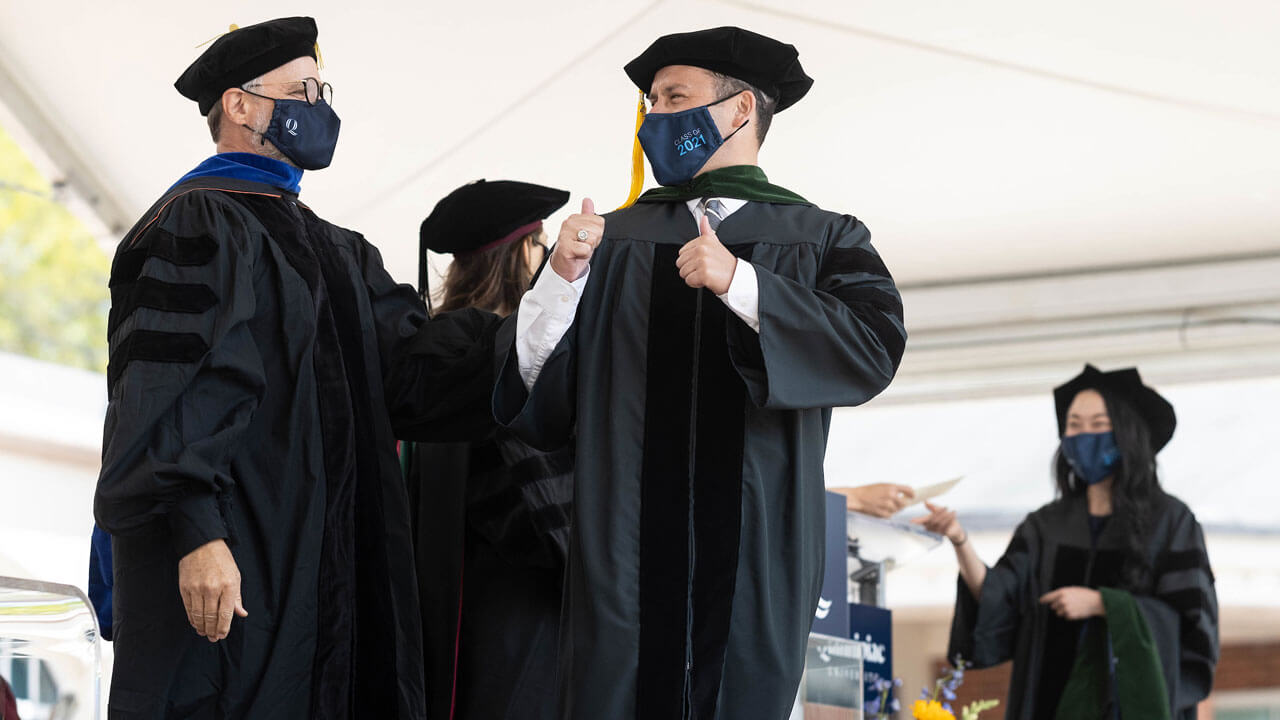 School of medicine graduate giving thumbs up after receiving his hood