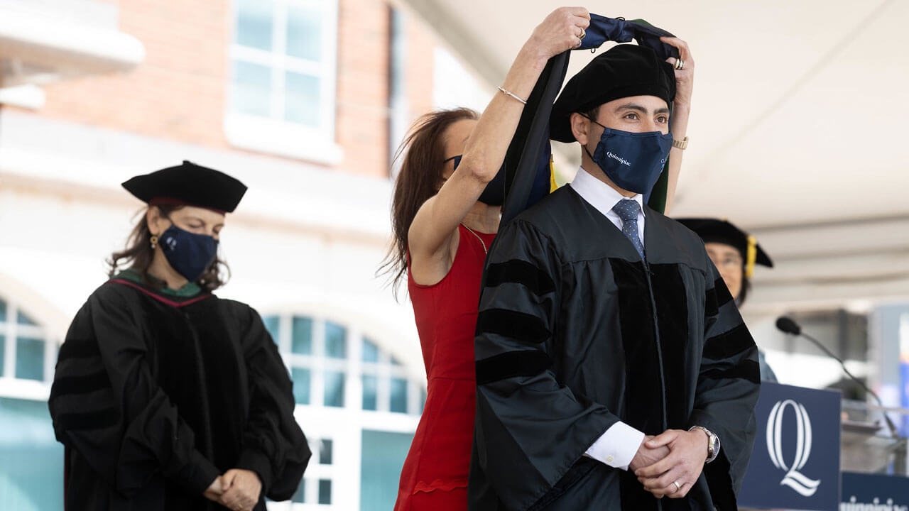 School of medicine graduate, Jeremy Fridling receiving his hood from his mother