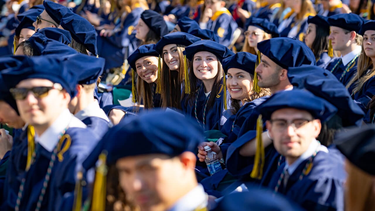 Four grads next to each other smile together
