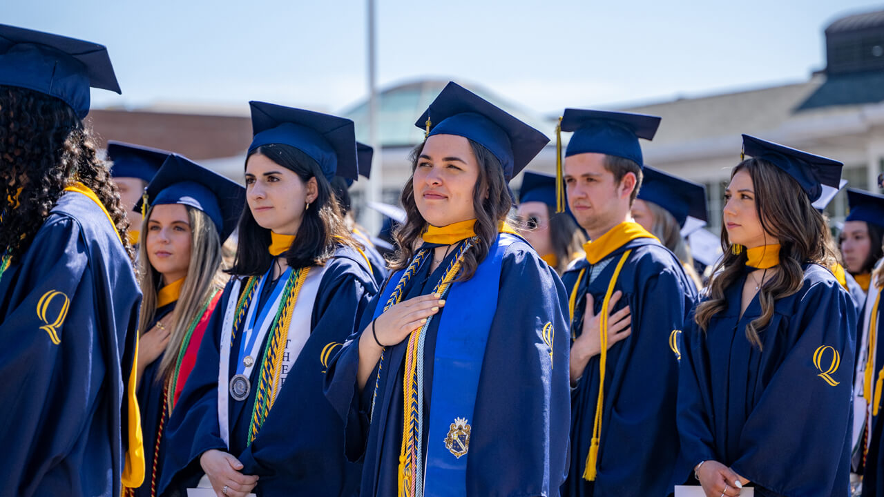 Half a dozen graduates put their hands over their hearts on the quad