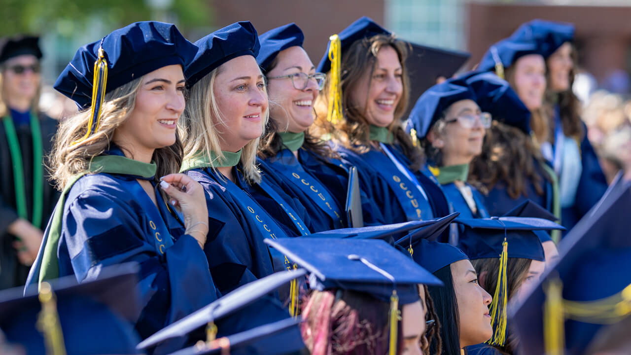 Newly hooded grads smile in excitement in the crowd
