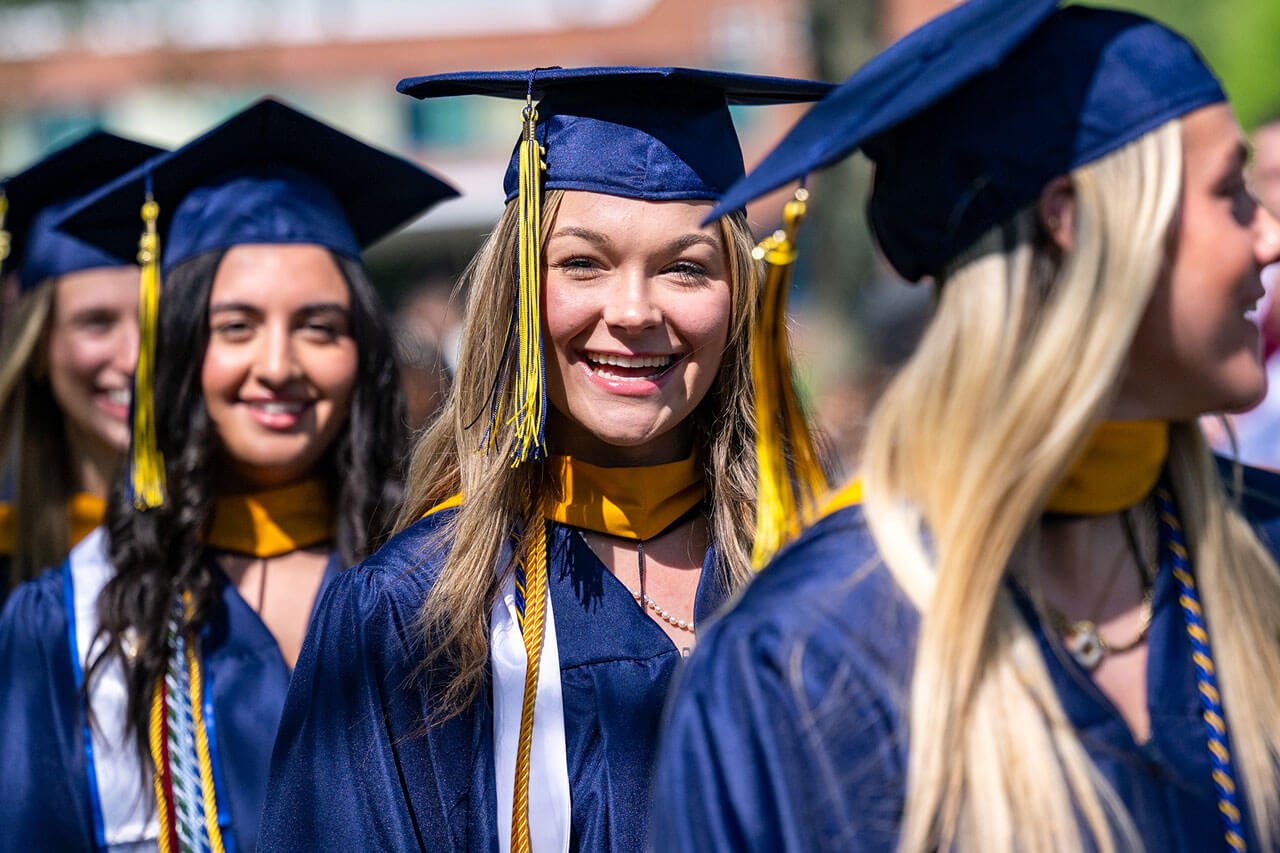 Graduates smile as they process into commencement.