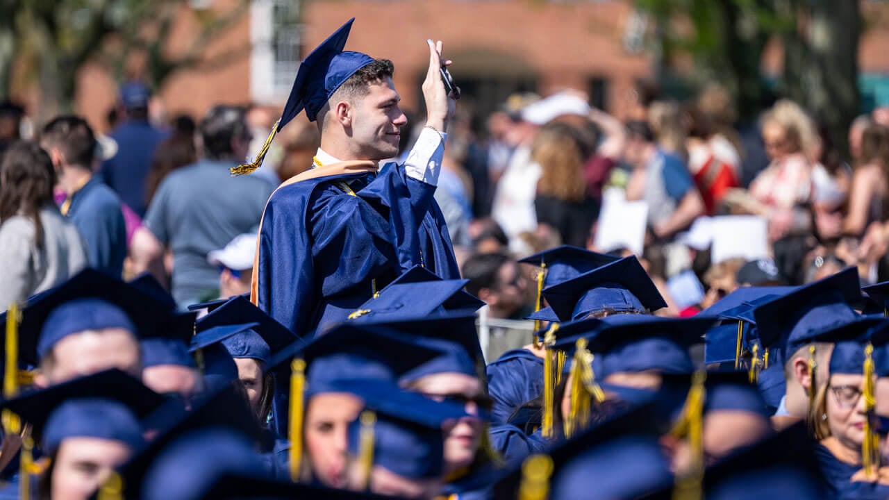 Graduate stands to wave in the crowd.