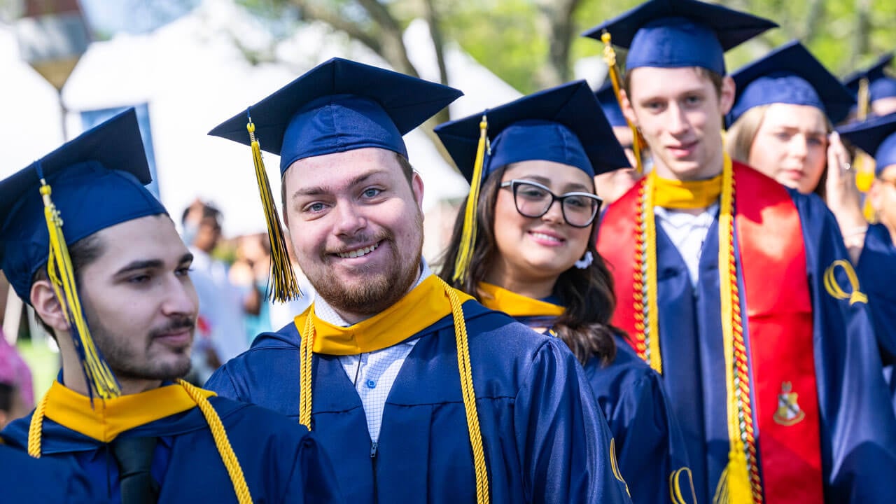Graduates smile as they process into commencement.