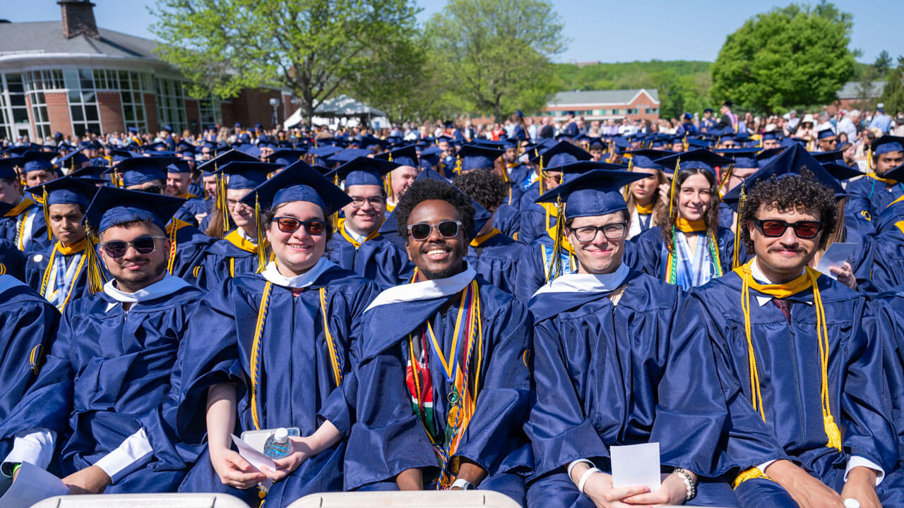 Graduates smile as they sit in the crowd.