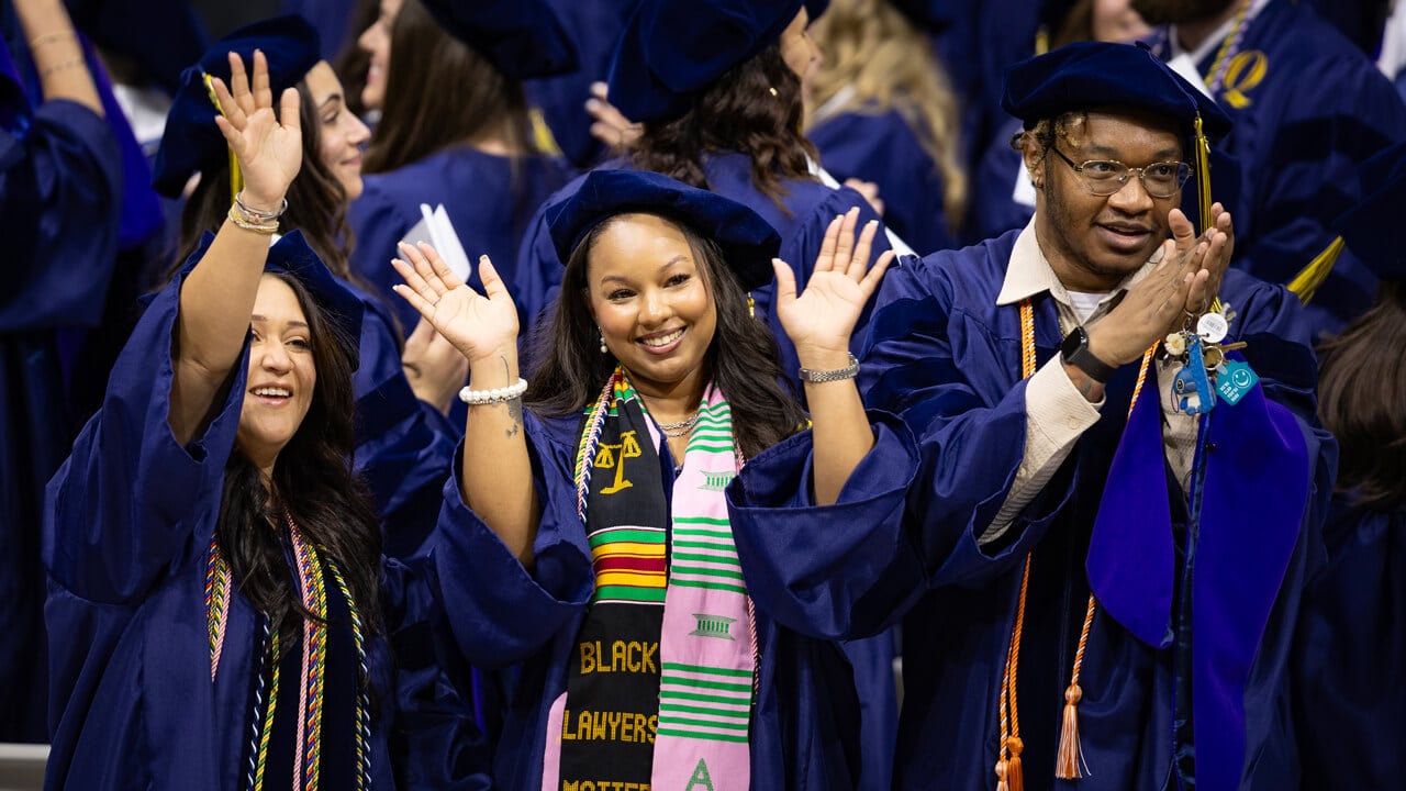 Graduates wave and cheer to their loved ones in the audience