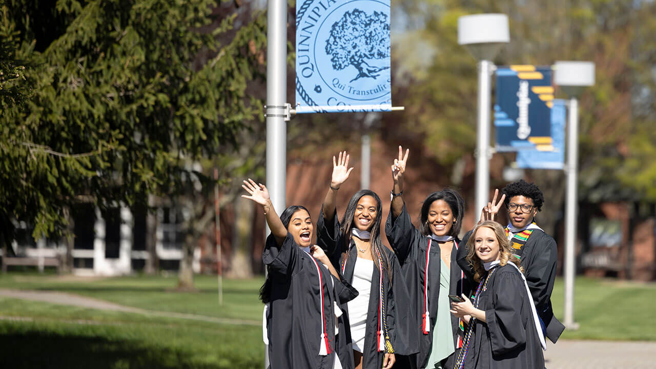 Graduates smile for a photo outside