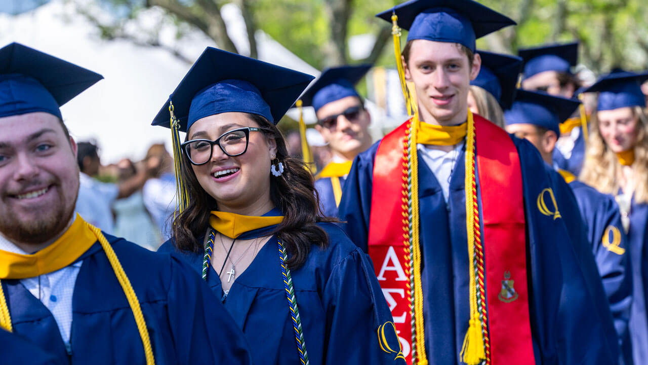 Graduates smile as they process into commencement.
