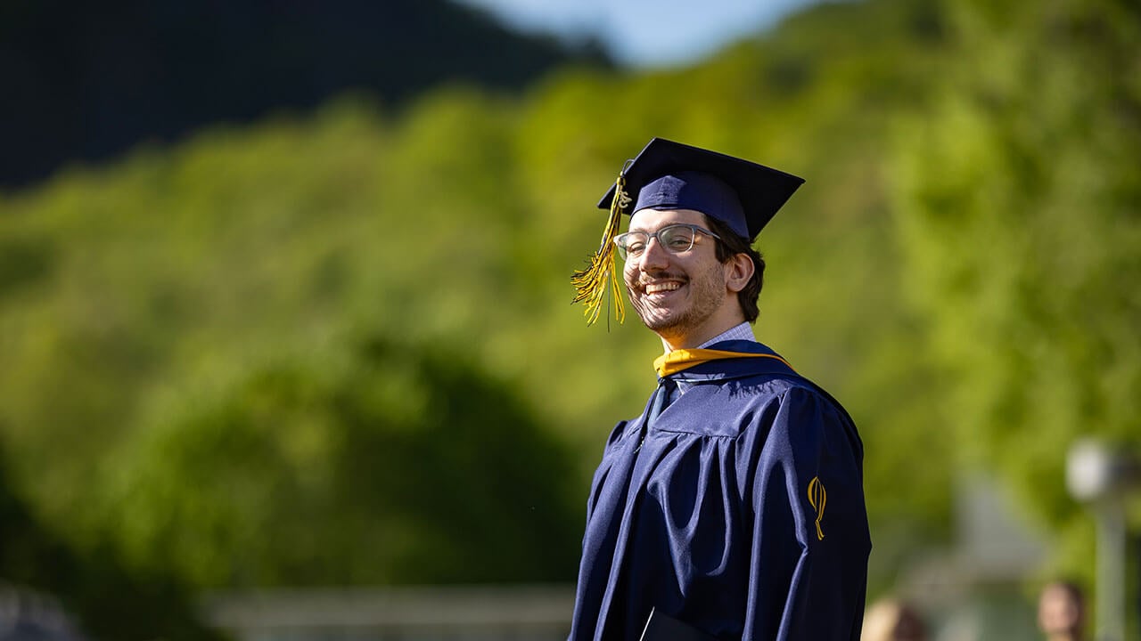 A graduate smiling with his graduate cap on