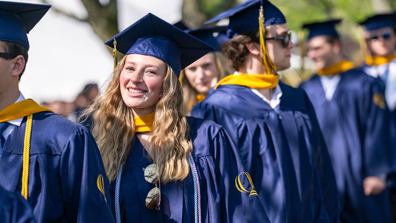 Graduate smiles as they process into commencement.