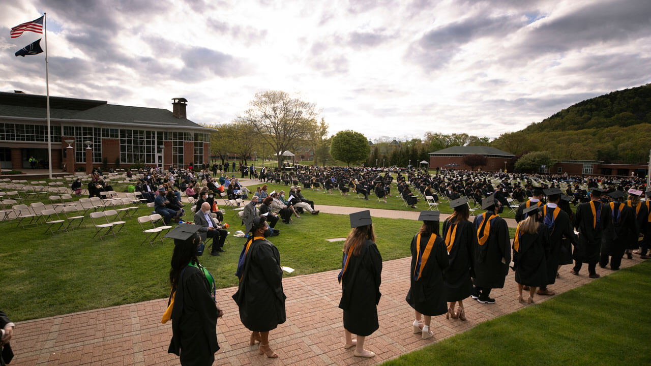 Graduates line up to recieve their degrees as the sun sets behind them