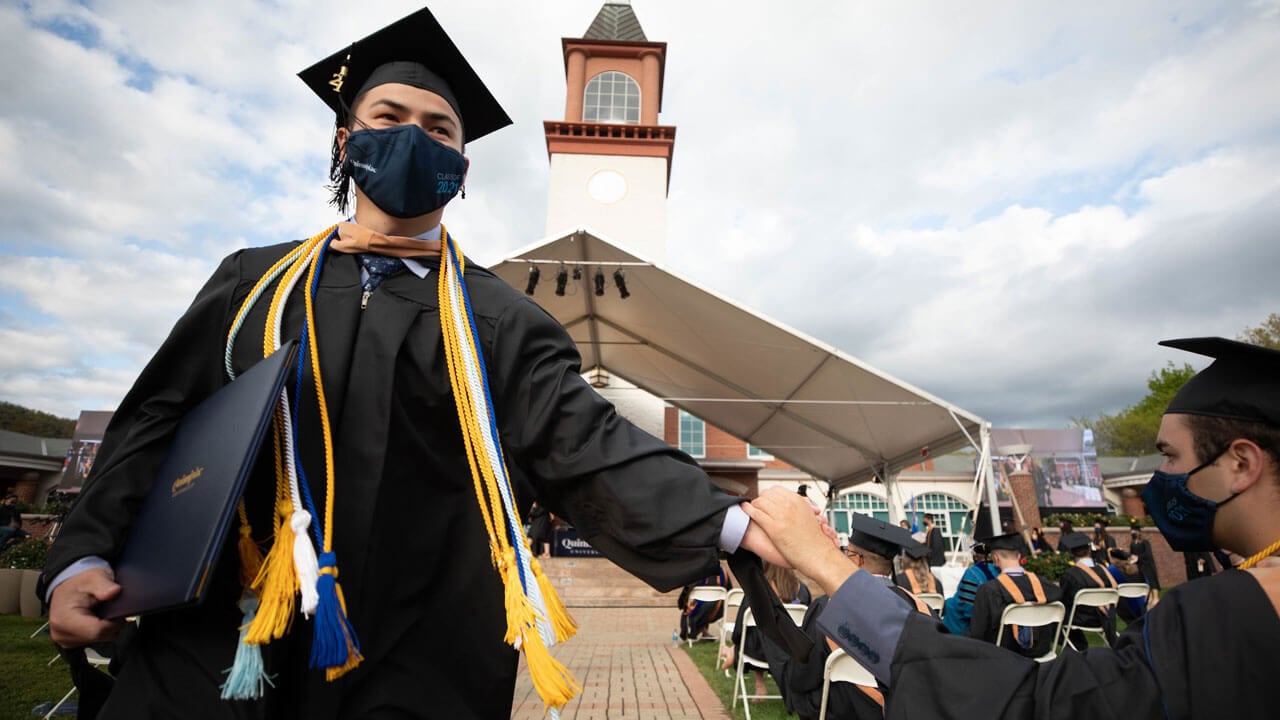 A graduate high fives as he walks back up the aisle