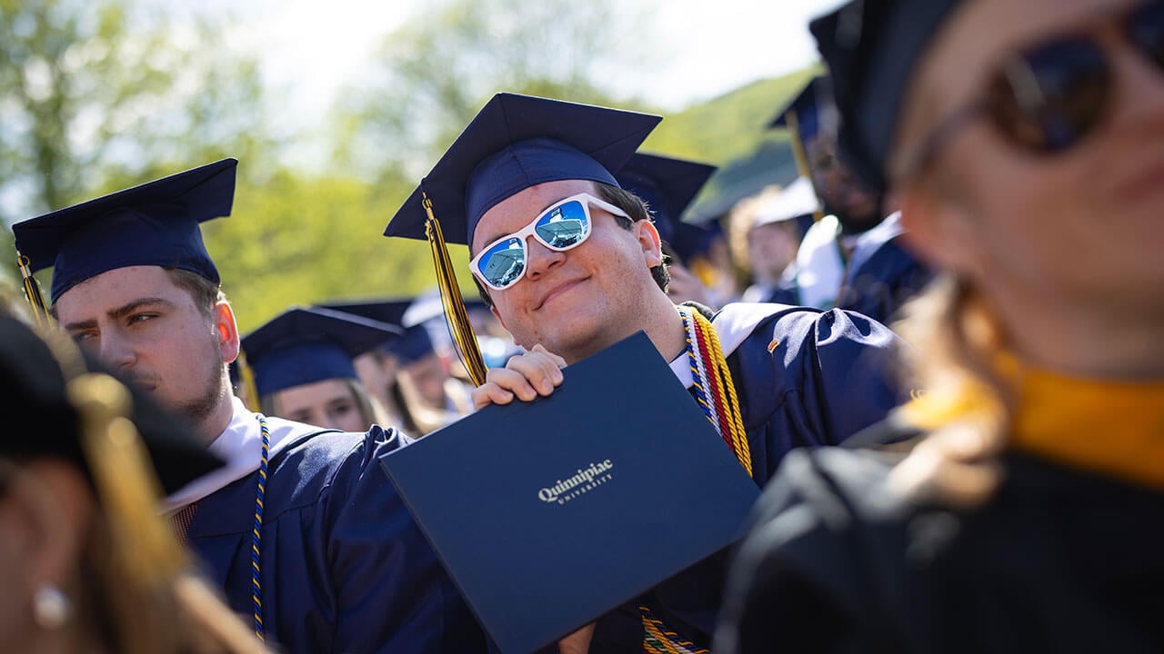graduate poses with their new diploma