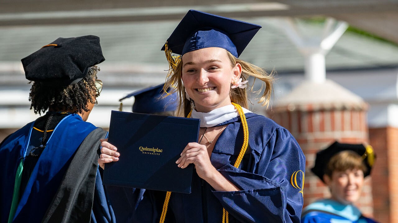 graduate smiles with new diploma